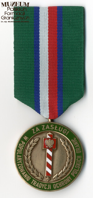 1. Nazwa własna: medal „Za zasługi w propagowaniu tradycji ochrony polskich granic”
2. Charakterystyka przedmiotu: medal powołany uchwałą nr 1 z 18.04.2019 r. Zarządu Stowarzyszenia Weteranów Polskich Formacji Granicznych, zaprojektowany przez Andrzeja Olichwiruka. Okrągły, barwy brązowej, bity w metalu, o średnicy 38 mm, częściowo emaliowany. Na awersie w polu środkowym znajduje się biało-czerwony słup graniczny z orłem państwowym na czerwonej tarczy herbowej. Po bokach wieniec laurowy spięty dołem czteropromienną gwiazdą. Na obwodzie medalu dwa pierścienie, pomiędzy którymi znajduje się napis „ZA ZASŁUGI W POPULARYZOWANIU TRADYCJI OCHRONY POLSKICH GRANIC” na tle zielonym. Na rewersie w polu środkowym logo Stowarzyszenia w postaci odznaki Korpusu Ochrony Pogranicza „Za Służbę Graniczną” wpisanej w orła wz. 19. Na obwodzie medalu dwa pierścienie, pomiędzy którymi znajduje się napis „STOWARZYSZENIE WETERANÓW POLSKICH FORMACJI GRANICZNYCH”. Wstążka odznaczenia ma szerokość 38 mm, składa się z dwóch zewnętrznych pasów koloru zielonego o szerokości po 11 mm, w środku pas biało-czerwony o szer. 10 mm, który oddzielony jest od zieleni dwoma paskami granatowymi o szer. po 3 mm. Szerokość baretki medalu równa jest szerokości wstążki, a wysokość wynosi 8 mm.
3. Czas powstania: 2019 r.
4. Hasła przedmiotowe: Straż Graniczna, miejsca pamięci
5. Miejsce przechowywania/właściciel: zbiory prywatne