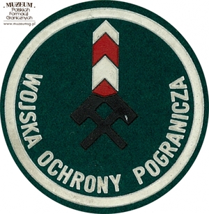 1. Nazwa własna: naszywka organizacyjna Górnośląskiej Brygady  Wojsk Ochrony Pogranicza
2. Charakterystyka przedmiotu: okrągła plakietka (o średnicy 6,6 cm)  wykonana z filcu na podkładzie płóciennym. Obwiedziona białym paskiem,  w dolnej części półkoliście napis „Wojska Ochrony Pogranicza”. W centrum  pola logo jednostki organizacyjnej – dwa skrzyżowane młotki górnicze  na tle słupa granicznego. Noszona na prawym przedramieniu marynarki  i płaszcza munduru wyjściowego
3. Czas powstania: lata 80. XX w.
4. Hasła przedmiotowe: Wojska Ochrony Pogranicza, umundurowanie
5. Miejsce przechowywania/właściciel: Śląski Oddział Straży Granicznej  w Raciborzu