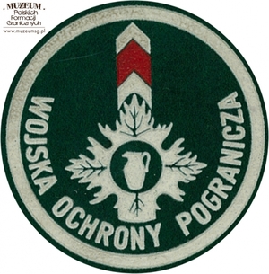 1. Nazwa własna: naszywka organizacyjna Sudeckiej Brygady  Wojsk Ochrony Pogranicza
2. Charakterystyka przedmiotu: okrągła plakietka (o średnicy 6,6 cm)  wykonana z filcu na podkładzie płóciennym. Obwiedziona białym paskiem,  w dolnej części półkoliście napis „Wojska Ochrony Pogranicza”. W centrum  pola logo jednostki organizacyjnej - ozdobny motyw roślinny z umieszczonym pośrodku dzbanem, na tle słupa granicznego. Noszona na prawym przedramieniu marynarki i płaszcza munduru wyjściowego
3. Czas powstania: lata 80. XX w.
4. Hasła przedmiotowe: Wojska Ochrony Pogranicza, umundurowanie
5. Miejsce przechowywania/właściciel: Śląski Oddział Straży Granicznej  w Raciborzu
