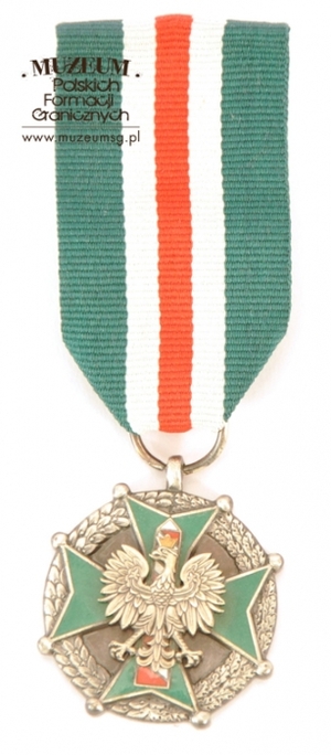 1.Nazwa własna: medal „Za Zasługi dla Straży Granicznej” – srebrny 
2.Charakterystyka przedmiotu: medal jest zmodyfikowaną kontynuacją nadawanej wcześniej odznaki: „Za Zasługi w Ochronie Granic PRL”. Ustanowiony został na mocy Ustawy z dnia 8 października 2004 r. Wykonany ze stopu metali o wymiarach: 3,5 x 3,5 x 0,3 cm. Na awersie obramowany jest wieńcem z liści laurowych i dębowych. W centralnym miejscu umieszczono czteroramienny, zielono emaliowany krzyż, zakończony na rogach kulkami i z wkomponowanym pośrodku wizerunkiem godła państwowego. Orzeł osadzony jest na tle słupa granicznego, którego pasy są emaliowane w kolorze białym i czerwonym, a kontury w kolorze szarym. Na rewersie, w wypukłym konturze przedstawiającym terytorium i granice Rzeczypospolitej Polskiej, umieszczony został napis: „ZA ZASŁUGI – DLA – STRAŻY GRANICZNEJ”. Medal zawieszony jest na wstążce koloru zielonego o szer. 3,5 cm. Przez środek wstążki przebiega biało-czerwono-biały pasek o szerokości 1,5 cm. Medal został przekazany przez Biuro Kadr i Szkolenia Komendy Głównej Straży Granicznej w Warszawie
3.Czas powstania: 2004 r.
4.Hasła przedmiotowe: Straż Graniczna, odznaczenia 
5.Miejsce przechowywania/właściciel: Centralny Ośrodek Szkolenia SG w Koszalinie