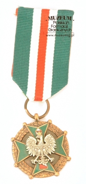 1.Nazwa własna: medal „Za Zasługi dla Straży Granicznej” – brązowy
2.Charakterystyka przedmiotu: medal jest zmodyfikowaną kontynuacją nadawanej wcześniej odznaki: „Za Zasługi w Ochronie Granic PRL”. Ustanowiony został na mocy Ustawy z dnia 8 października 2004 r. Wykonany ze stopu metali o wymiarach: 3,5 x 3,5 x 0,3 cm. Na awersie obramowany jest wieńcem z liści laurowych i dębowych. W centralnym miejscu umieszczono czteroramienny, zielono emaliowany krzyż, zakończony na rogach kulkami i z wkomponowanym pośrodku wizerunkiem godła państwowego. Orzeł osadzony jest na tle słupa granicznego, którego pasy są emaliowane w kolorze białym i czerwonym, a kontury w kolorze szarym. Na rewersie, w wypukłym konturze przedstawiającym terytorium i granice Rzeczypospolitej Polskiej, umieszczony został napis: „ZA ZASŁUGI – DLA – STRAŻY GRANICZNEJ”. Medal zawieszony jest na wstążce koloru zielonego o szer. 3,5 cm. Przez środek wstążki przebiega biało-czerwono-biały pasek o szerokości 1,5 cm. Medal został przekazany przez Biuro Kadr i Szkolenia Komendy Głównej Straży Granicznej w Warszawie
3.Czas powstania: 2004 r.
4.Hasła przedmiotowe: Straż Graniczna, odznaczenia 
5.Miejsce przechowywania/właściciel: Centralny Ośrodek Szkolenia SG w Koszalinie