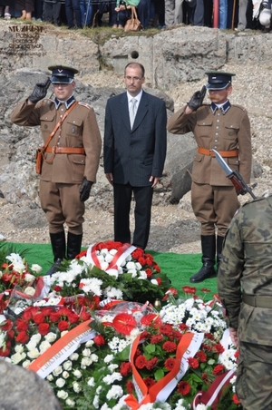 1. Tytuł: delegacja oddająca honory po złożeniu kwiatów
2. Opis obrazu: członkowie Grupy Rekonstrukcji Centralnej Szkoły Podoficerskiej Korpusu Ochrony Pogranicza w Osowcu wraz z Dariuszem Szymanowskim – prezesem Stowarzyszenia „Wizna 1939” po złożeniu kwiatów
3. Data wydarzenia: 10.09.2011 r.
4. Osoby widoczne: Dariusz Szymanowski – prezes Stowarzyszenia „Wizna 1939”  (w środku)
5. Hasła przedmiotowe: miejsca pamięci
6. Opis techniczny: oryginał, kolorowe
7. Autor: Rafał Pazio
8. Miejsce przechowywania/właściciel: Rafał Pazio