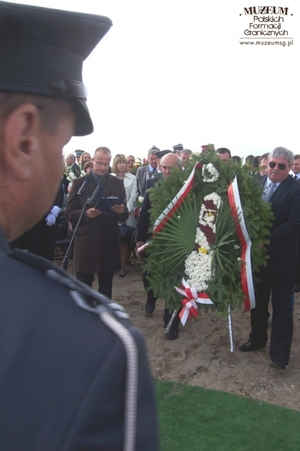 1. Tytuł: ceremonia pogrzebowa
2. Opis obrazu: delegacja z wieńcem w kształcie odznaki Korpusu Ochrony Pogranicza
3. Data wydarzenia: 10.09.2011 r.
4. Osoby widoczne: Adam Sikorski - dziennikarz TVP Lublin, (trzymający wieniec z prawej strony) Wojciech Tomaszewski – kapitan pilot lotnictwa cywilnego, autor wieńca (trzymający wieniec z lewej strony)
5. Hasła przedmiotowe: miejsca tradycji
6. Opis techniczny: oryginał, kolorowe
7. Autor: Maria Rubas
8. Miejsce przechowywania/właściciel: Maria Rubas