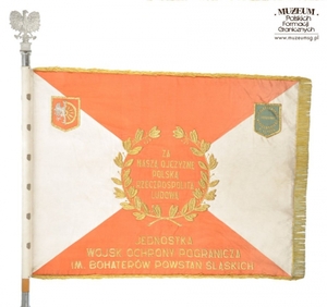 1.Nazwa własna: Sztandar Jednostki Wojsk Ochrony Pogranicza im. Bohaterów Powstań Śląskich.
2.Charakterystyka przedmiotu: biały płat (130 x 100 cm) zszyty z dwóch trójkątów koloru białego (bocznych) i dwóch koloru czerwonego (górny i dolny). Pośrodku, na czerwonym tle  obwiedzionym dwiema złotymi gałązkami wawrzynu, umieszczono wizerunek orła państwowego. Na stronie odwrotnej widnieje napis, otoczony gałązkami wawrzynu „Za – Naszą Ojczyznę – Polską – Rzeczpospolitą – Ludową”, a poniżej nazwa jednostki: „Jednostka – Wojsk Ochrony Pogranicza – Im. Bohaterów Powstań Śląskich”. W lewym górnym rogu na zszyciach biało-czerwonych pól: herb Raciborza, a w prawym rogu zielona tarcza ze złoconą obwódką i złotym napisem: „Społeczeństwo – Regionu – Raciborskiego – 8 VI.1986 r.”. Płat sztandaru obszyty złotymi frędzlami
3.Czas powstania: 1986 r.
4.Hasła przedmiotowe: Wojska Ochrony Pogranicza, sztandary
5.Miejsce przechowywania/ właściciel: Centralny Ośrodek Szkolenia Straży Granicznej w Koszalinie